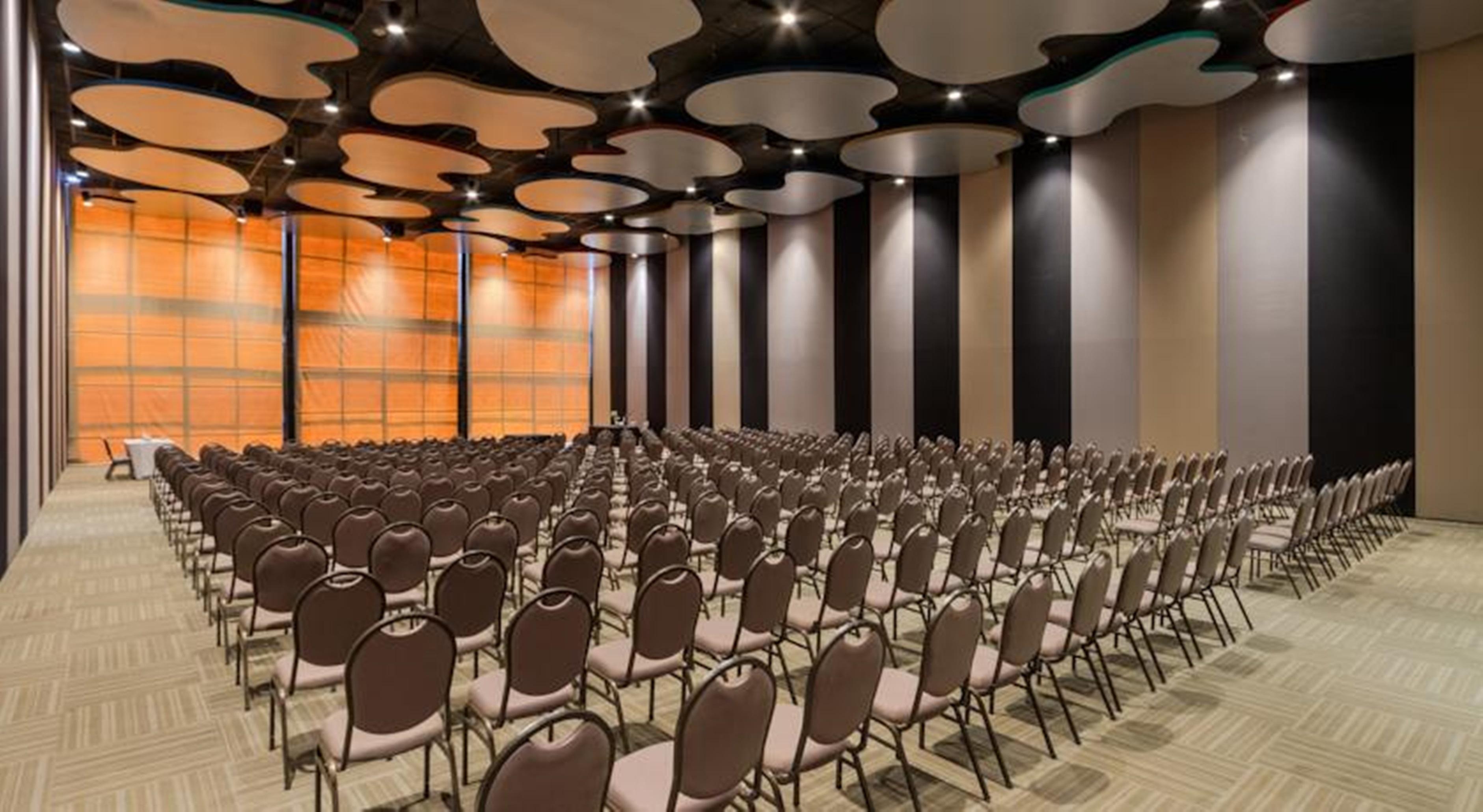 Royal Tulip Brasilia Alvorada Hotel Exterior photo The photo shows a large conference or event space filled with numerous empty chairs arranged in rows. The chairs have a simple design, with cushioned seats and backs. The walls of the room are decorated with a combination of dark and light tones, and