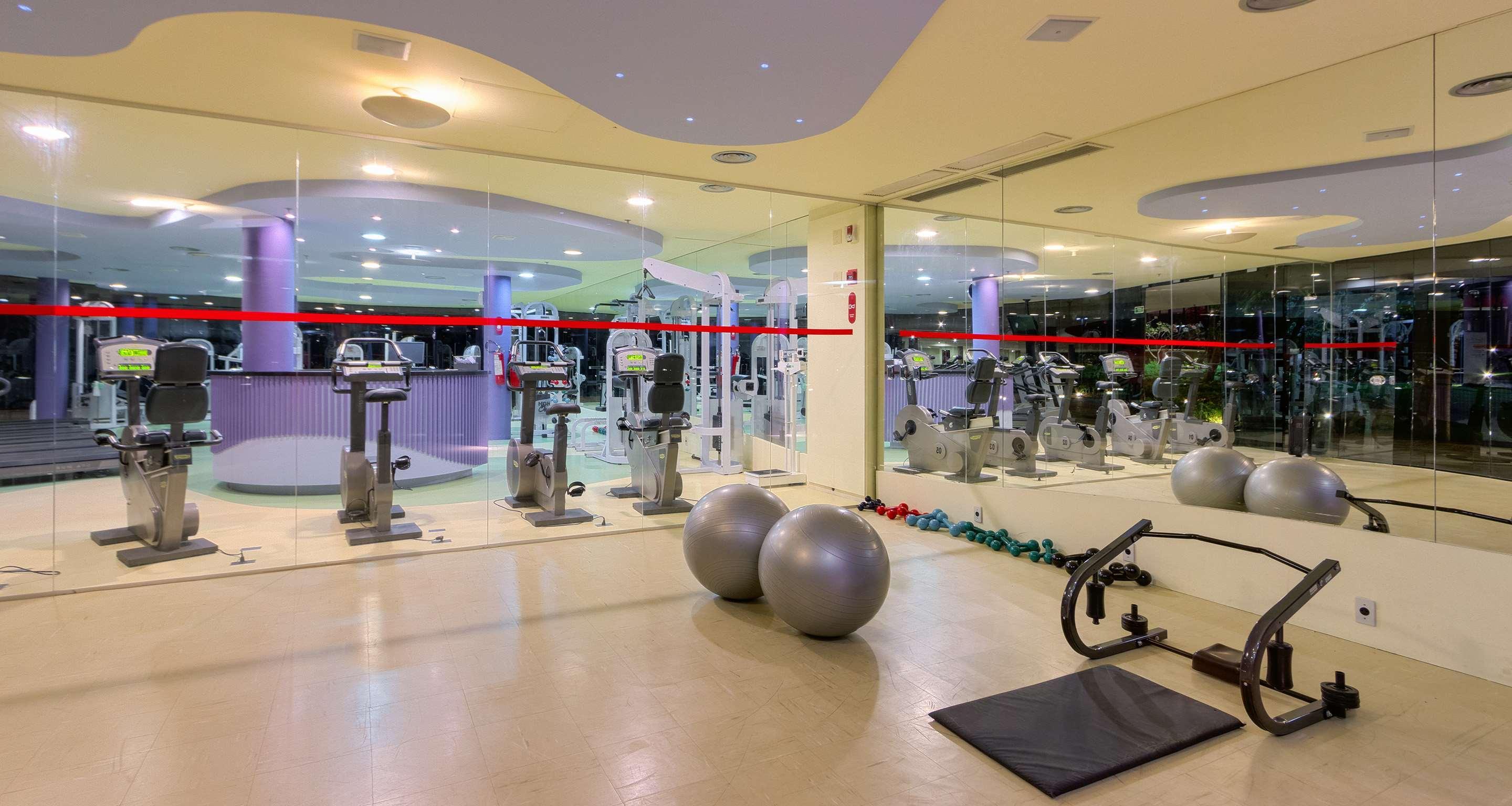 Royal Tulip Brasilia Alvorada Hotel Exterior photo The photo depicts a gym or fitness area. In the foreground, there are two large exercise balls and a mat on the floor. Behind them, there is a wall of mirrors that reflects various gym equipment, including exercise machines and bikes. The lighting in